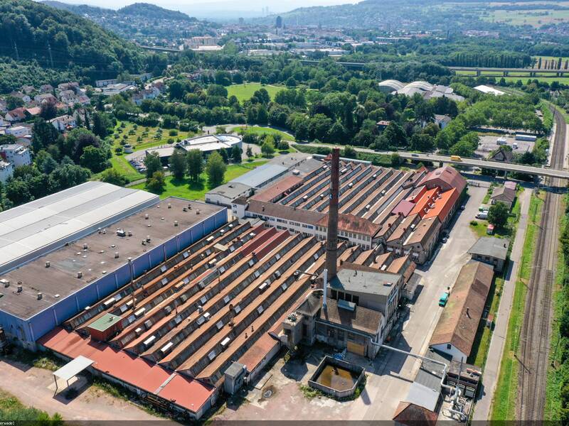 Das Lauffenmühle Areal von oben mit Industriegebäuden und Schornstein. Im Hintergrund die Stadt Lörrach